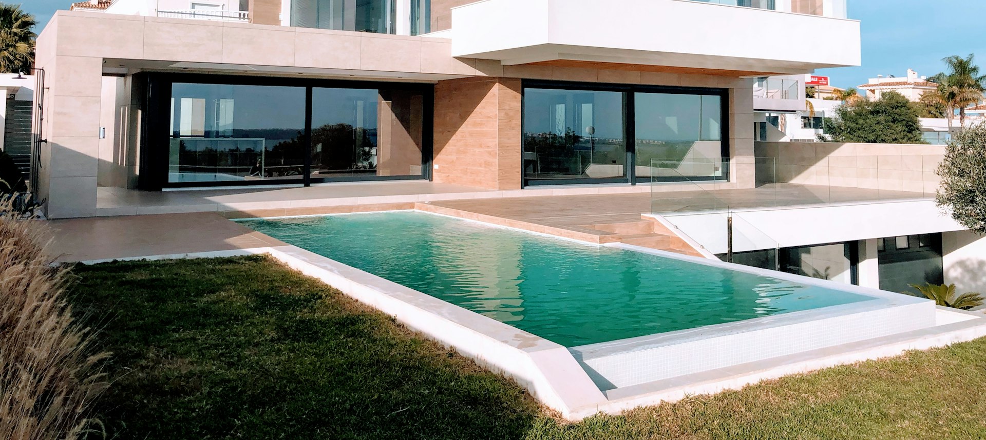 Fachada de residência contemporânea com pedra, vidro e paisagismo